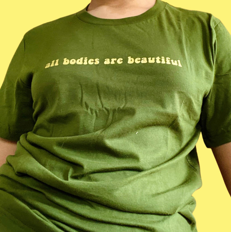 “All bodies are beautiful” gold on dark green t-shirt