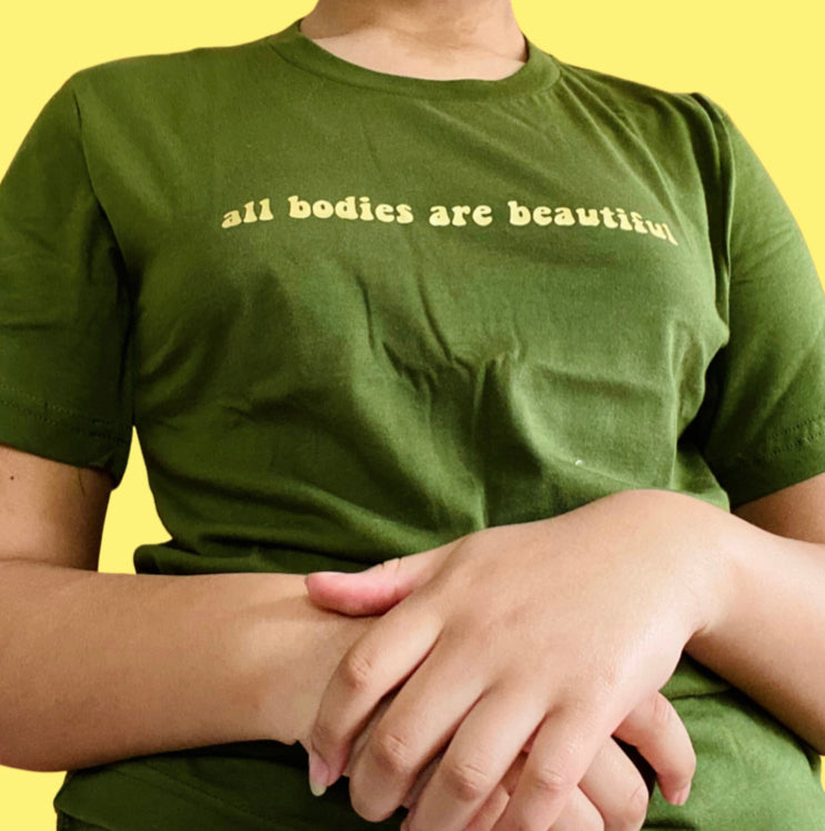 “All bodies are beautiful” gold on dark green t-shirt