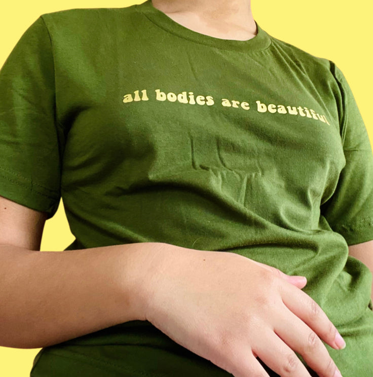 “All bodies are beautiful” gold on dark green t-shirt