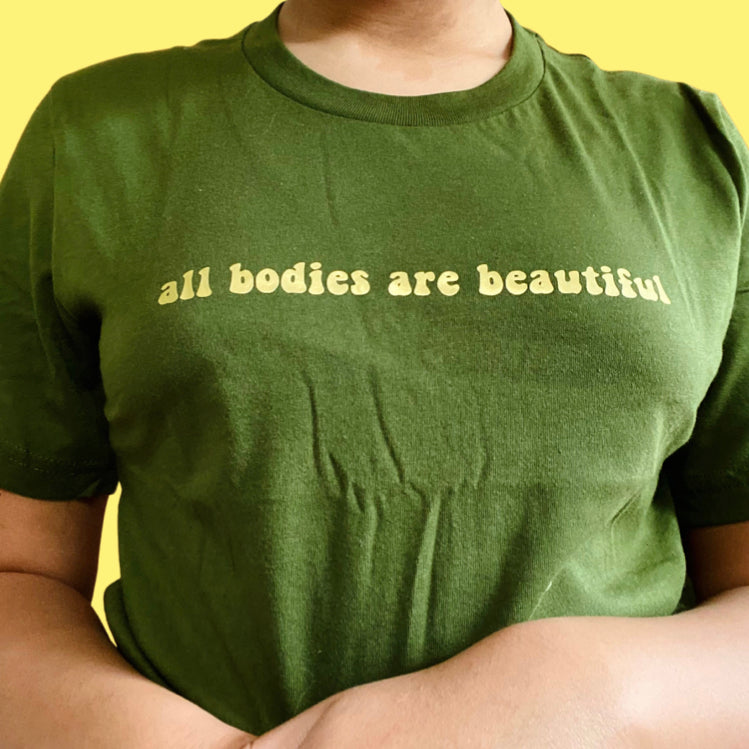 “All bodies are beautiful” gold on dark green t-shirt